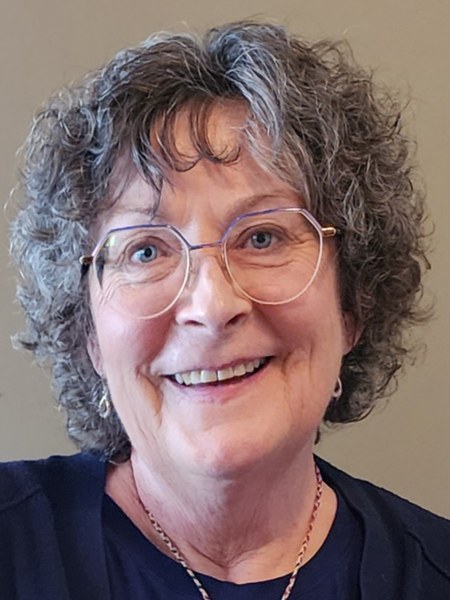 Rev. Janet Taylor, smiling, with curly grey hair and glasses