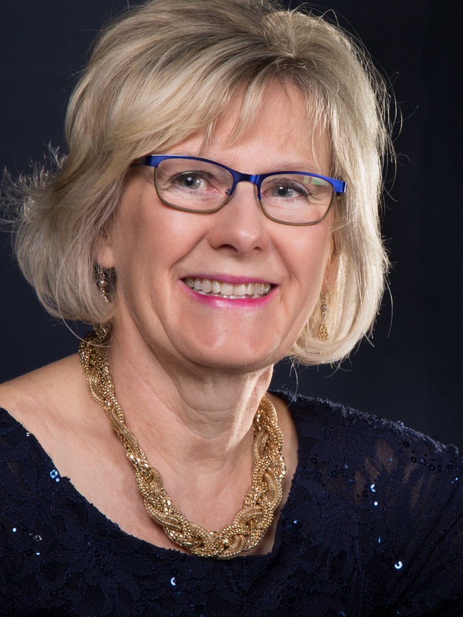 Dr. Marnie Giesbrecht smiling, seated beside a grand piano