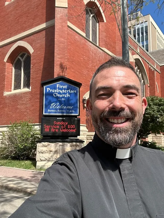 Rev. Dr. Mark Chiang outside the church, beside the sign on 105 Street