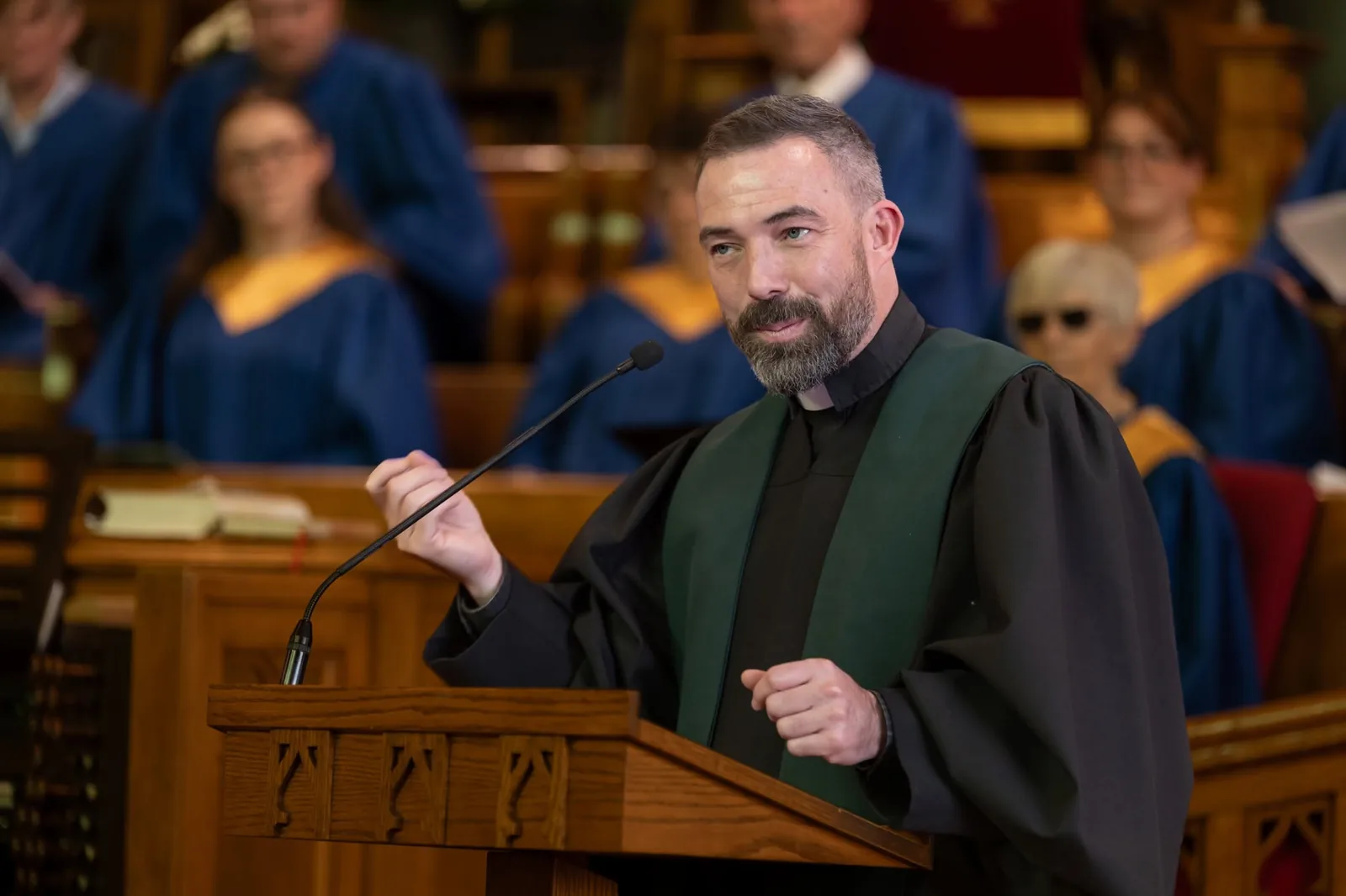 A minister preaching from the pulpit at First Presbyterian Church, with the choir seated behind him